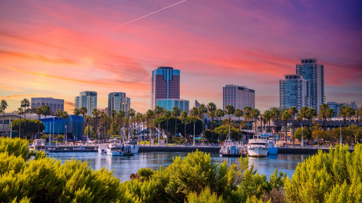 The Long Beach skyline with boats in the harbor during sunset.