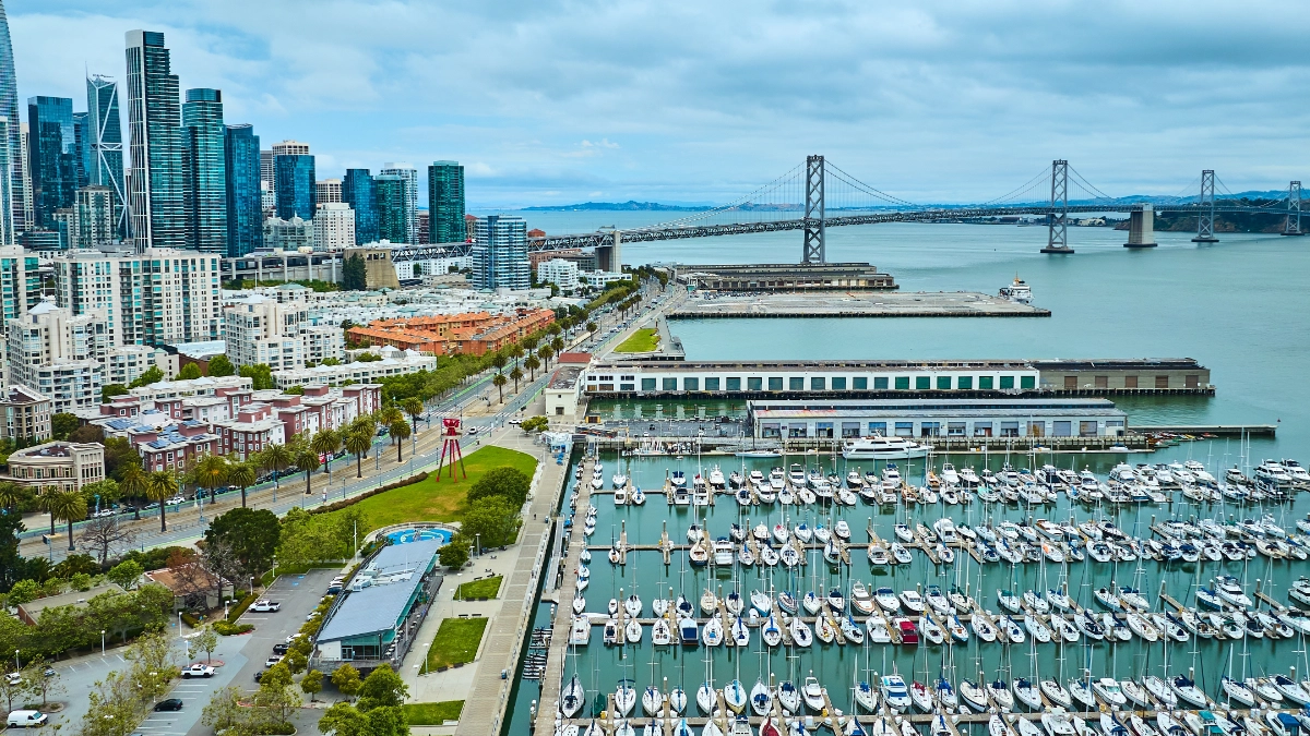 Boats docked at a marina with the San Francisco skyline and Golden Gate Bridge in the background.